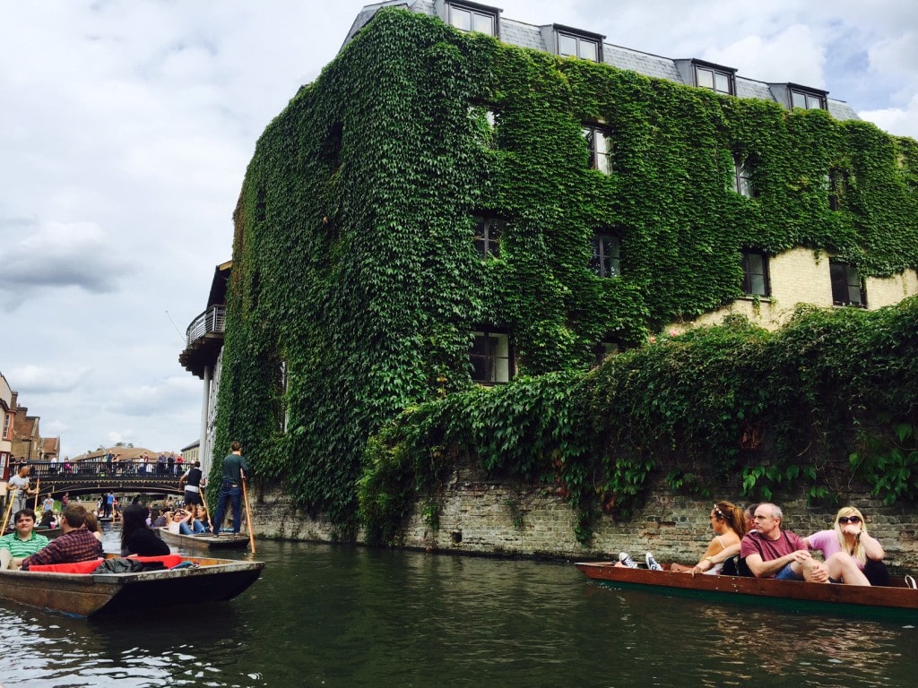 Punting on the Cam river by an ivy covered building - "Punting in Cambridge, England – And I am not Talking about Football" - Two Traveling Texans